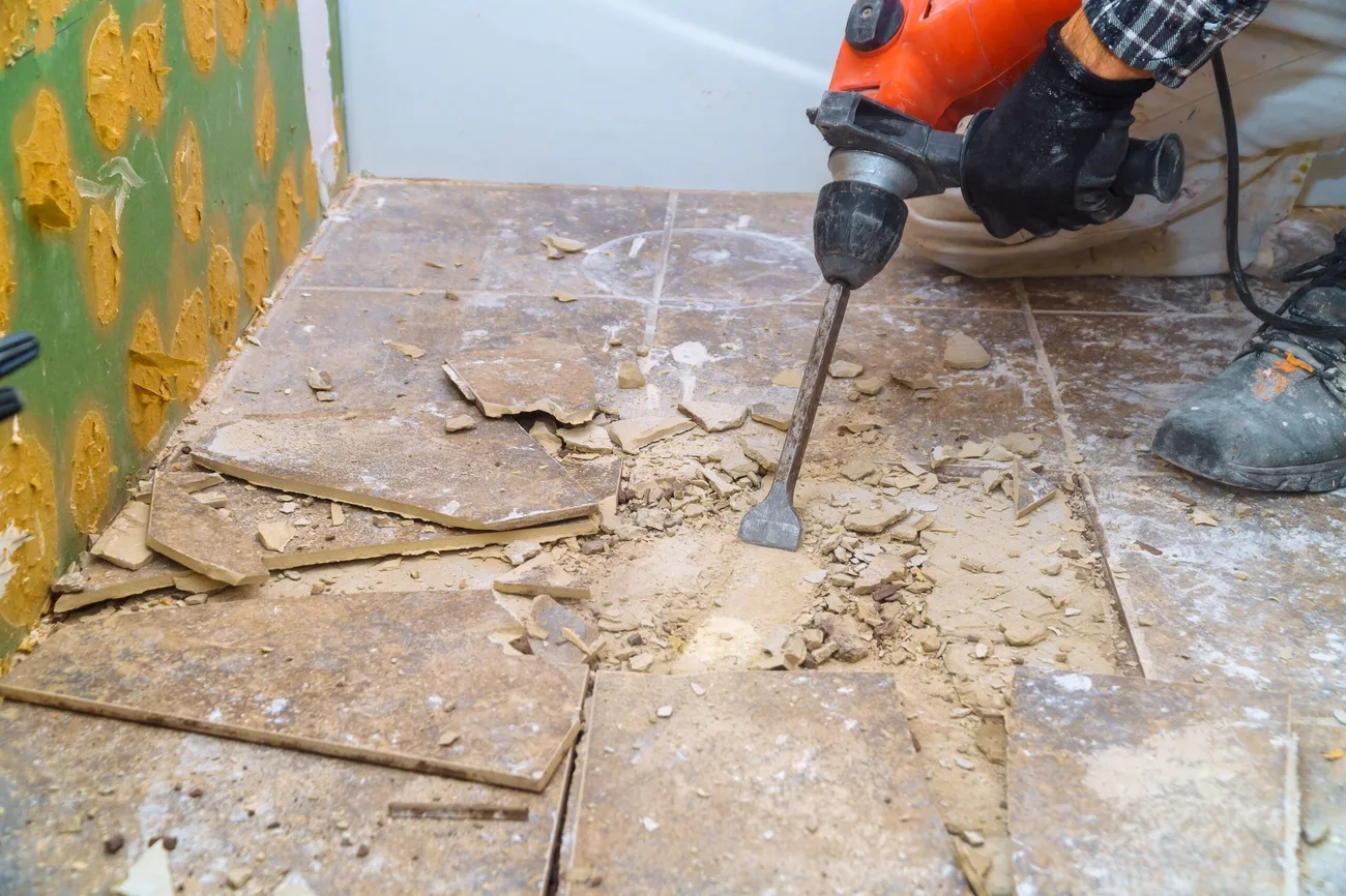 Rotary hammer chisel breaking old ceramic floor tile and thinset loose